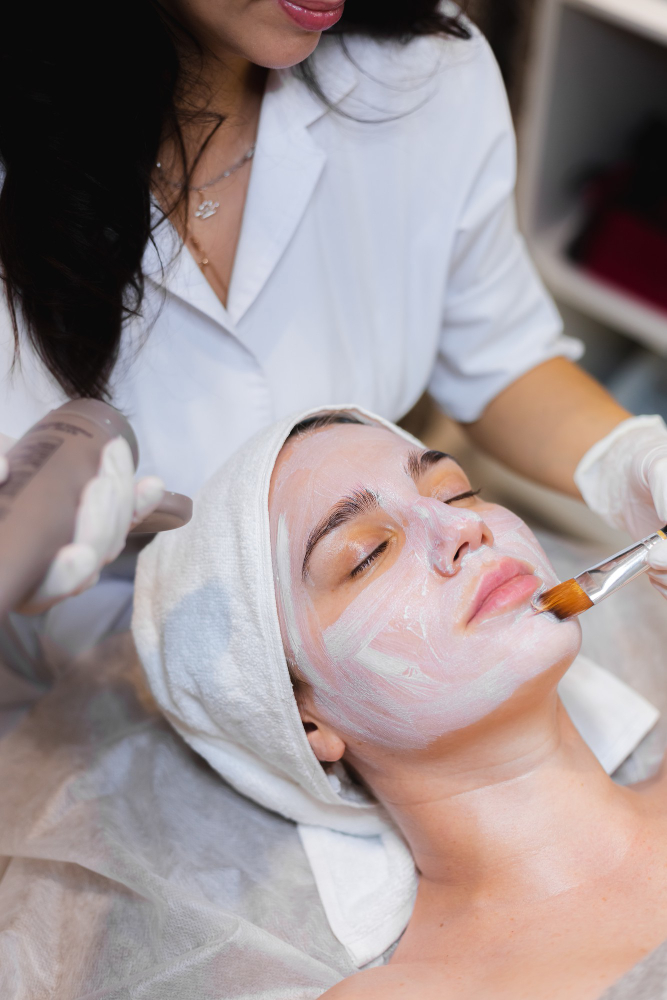beautician-with-brush-applies-white-moisturizing-mask-face-young-girl-client-spa-beauty-salon (1)